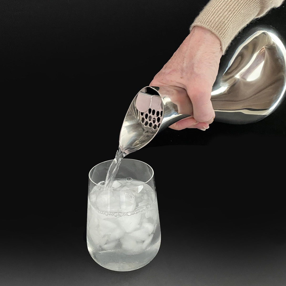 Water poured from the VAGNBYS Swan Carafe into a glass of ice, the ice cube separator holding the ice back